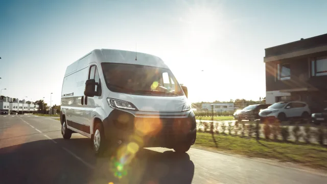 New Delivery Van Driving Through the suburban Town Area on a sunny day.