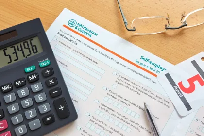 self-employed hmrc revenue and customs tax form on desk with calculator and pair of glasses