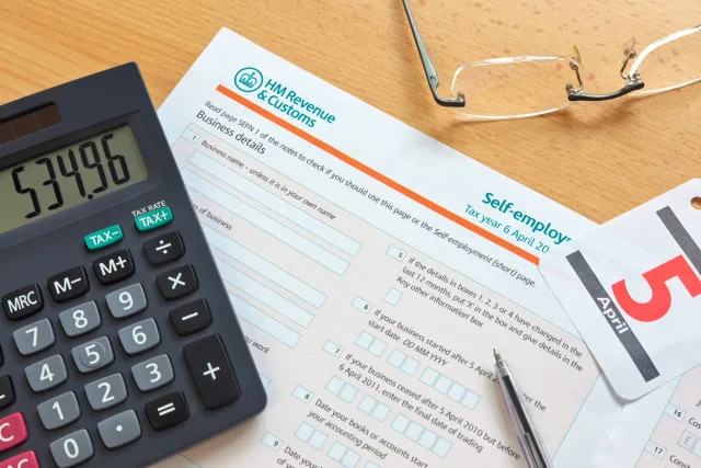 self-employed hmrc revenue and customs tax form on desk with calculator and pair of glasses