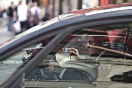 Man wearing glasses and smoking in a car.